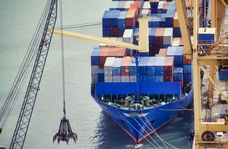 Maritime Crisis 2026: Shipping Losses and Rising Risks Maritime Crisis 2026 showing a container ship docked beside cargo cranes at a major commercial port